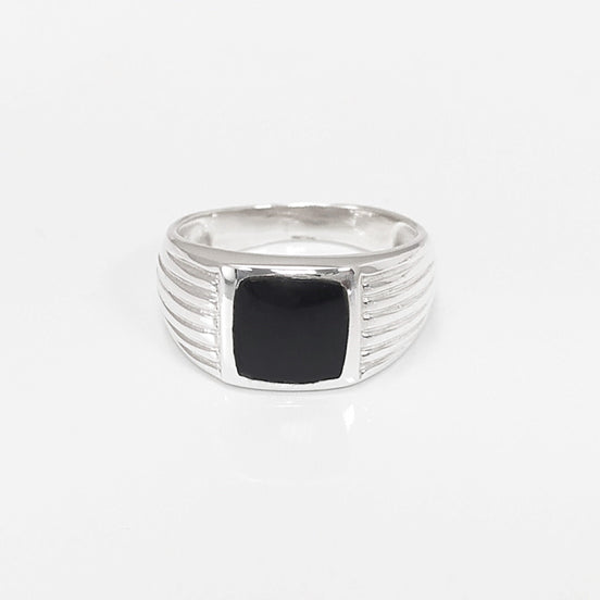 Peut inclure: Une bague en argent avec une pierre carrée noire sertie au centre. La bande de la bague a un design texturé.