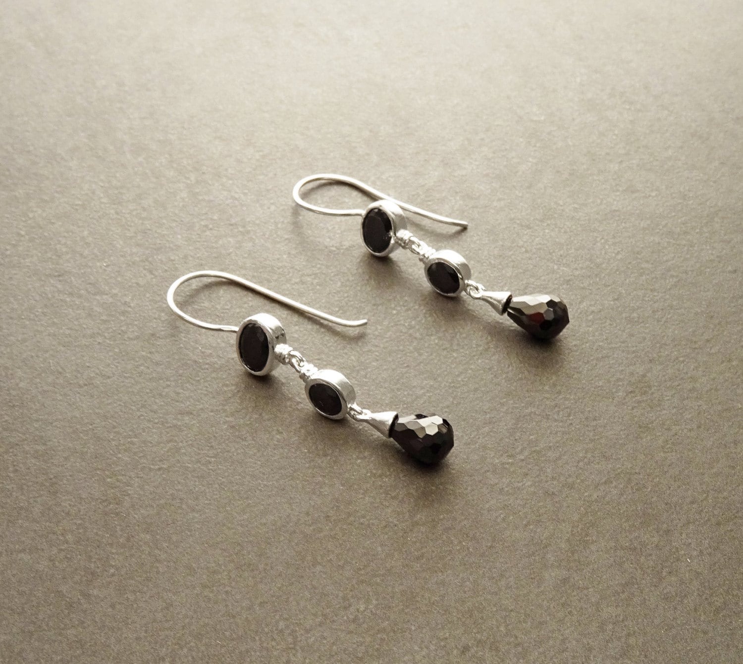 Boucles d'oreilles pendantes en argent 925 avec trois pierres Cz zirconium noires. La pierre du haut est ronde, la pierre du milieu est ovale et la pierre du bas a la forme d'une larme. Longues boucles d'oreilles modernes à crochets vendues par KRAMIKE Paris