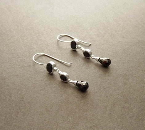 Boucles d'oreilles pendantes en argent 925 avec trois pierres Cz zirconium noires. La pierre du haut est ronde, la pierre du milieu est ovale et la pierre du bas a la forme d'une larme. Longues boucles d'oreilles modernes à crochets vendues par KRAMIKE Paris