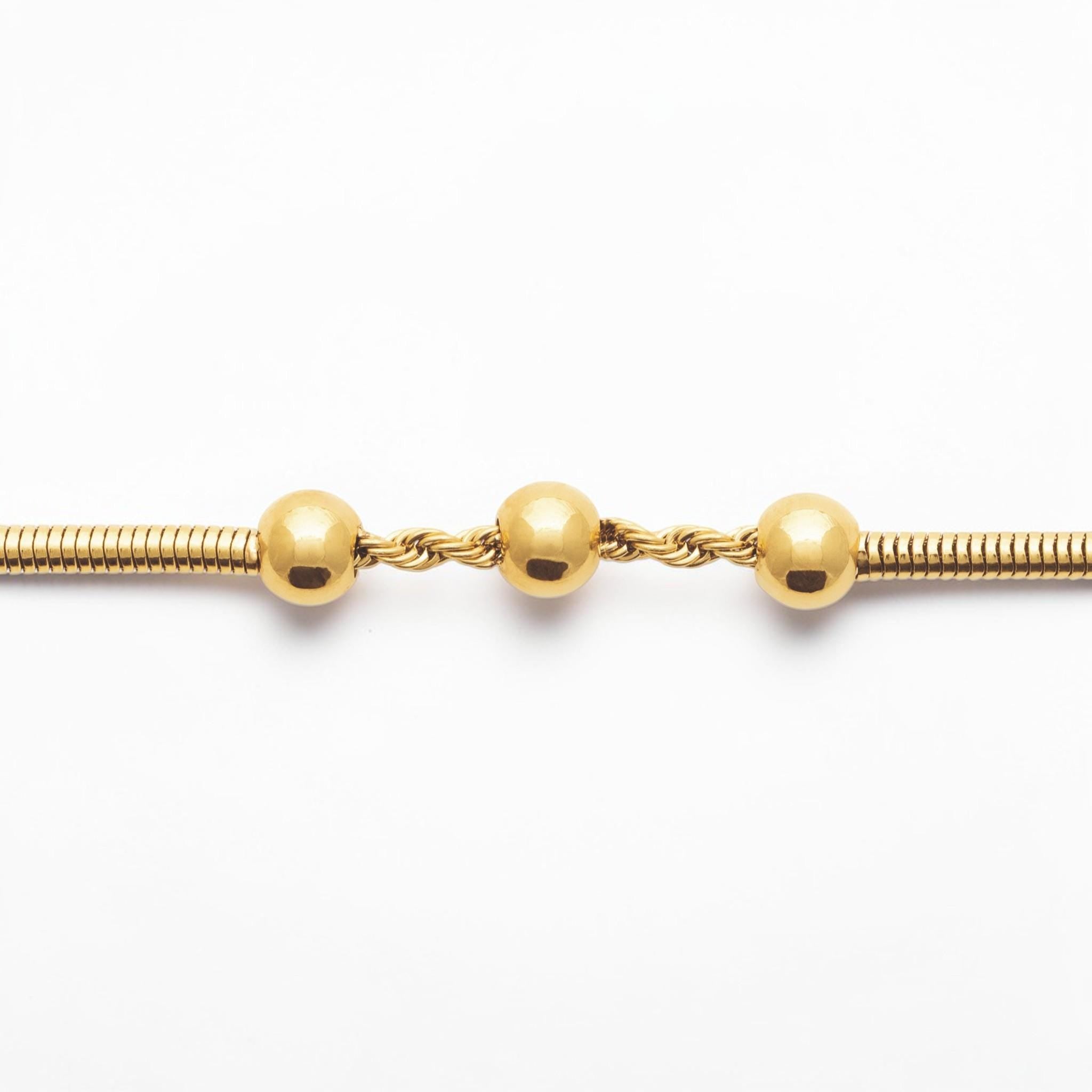 Focus on a Minimalist 18K Gold Filled Snake Chain with Triple Bead.

Product type: bracelet
Material: 18K gold filled, stainless steel
Length : adjustable 18-20cm
Width : 3mm
Clasp : lobster clasp
Color: yellow gold
Style: minimalist, dainty, elegant
Design details: snake chain, three polished beads, twisted connector detail
Best for: everyday wear, layering, gifting, minimalist jewelry lovers