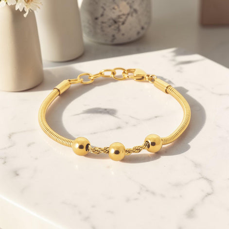 A Minimalist 18K Gold Filled Snake Chain with Triple Bead, lay on a table.
Product type: bracelet
Material: 18K gold filled, stainless steel
Length : adjustable 18-20cm
Width : 3mm
Clasp : lobster clasp
Color: yellow gold
Style: minimalist, dainty, elegant
Design details: snake chain, three polished beads, twisted connector detail
Best for: everyday wear, layering, gifting, minimalist jewelry lovers