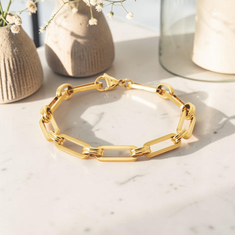 A 18K Gold Filled Paperclip Bracelet lay on a marble table.
Product type: bracelet
Material:  18K Gold Filled, stainless steel base
Color: yellow gold
Style: minimalist, modern, elegant
Design details: elongated rectangular paperclip links, polished finish, geometric chain design, lobster clasp
Best for: everyday wear, layering, gifting, minimalist jewelry lovers, modern capsule wardrobes