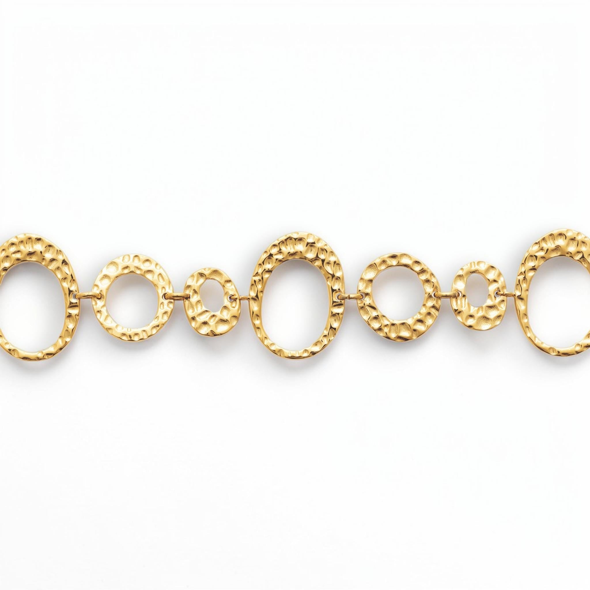 focus view of a geometric bracelet 
Product type: bracelet
Material:  18K Gold Filled, stainless steel base
Color: yellow gold
Style: statement, geometric, elegant, modern
Design details: hammered open circle and oval links, graduated sizes, textured finish, airy openwork design, lobster clasp with extender
Best for: statement styling, special occasions, everyday elevated wear, gifting, artistic jewelry lovers