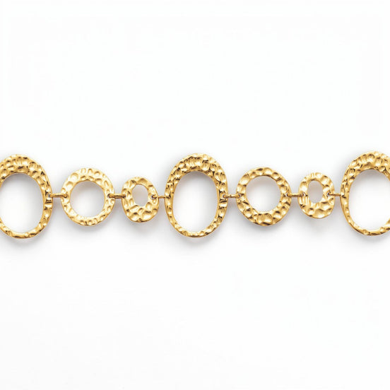 focus view of a geometric bracelet 
Product type: bracelet
Material:  18K Gold Filled, stainless steel base
Color: yellow gold
Style: statement, geometric, elegant, modern
Design details: hammered open circle and oval links, graduated sizes, textured finish, airy openwork design, lobster clasp with extender
Best for: statement styling, special occasions, everyday elevated wear, gifting, artistic jewelry lovers