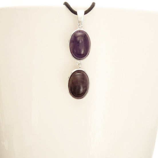 Peut inclure: Un collier en argent avec deux pierres d'améthyste de forme ovale. Les pierres sont d'une couleur violet foncé et sont serties d'argent.