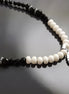 Peut inclure: Un collier de perles noires et blanches avec un pendentif en argent orné d'une pierre d'onyx noire et d'accents en nacre blanche.