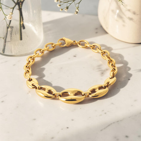 Here a view of the matching bracelet closed, placed on a table. It's a 18K Gold Filled coffee bean link bracelet with polished oval centerpiece links and a modern rounded chain design. Elegant, minimalist, and slightly bold, it is ideal for everyday wear, layering, and gifting.