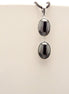 Peut inclure: Un collier avec un pendentif en argent avec deux pierres ovales noires.
