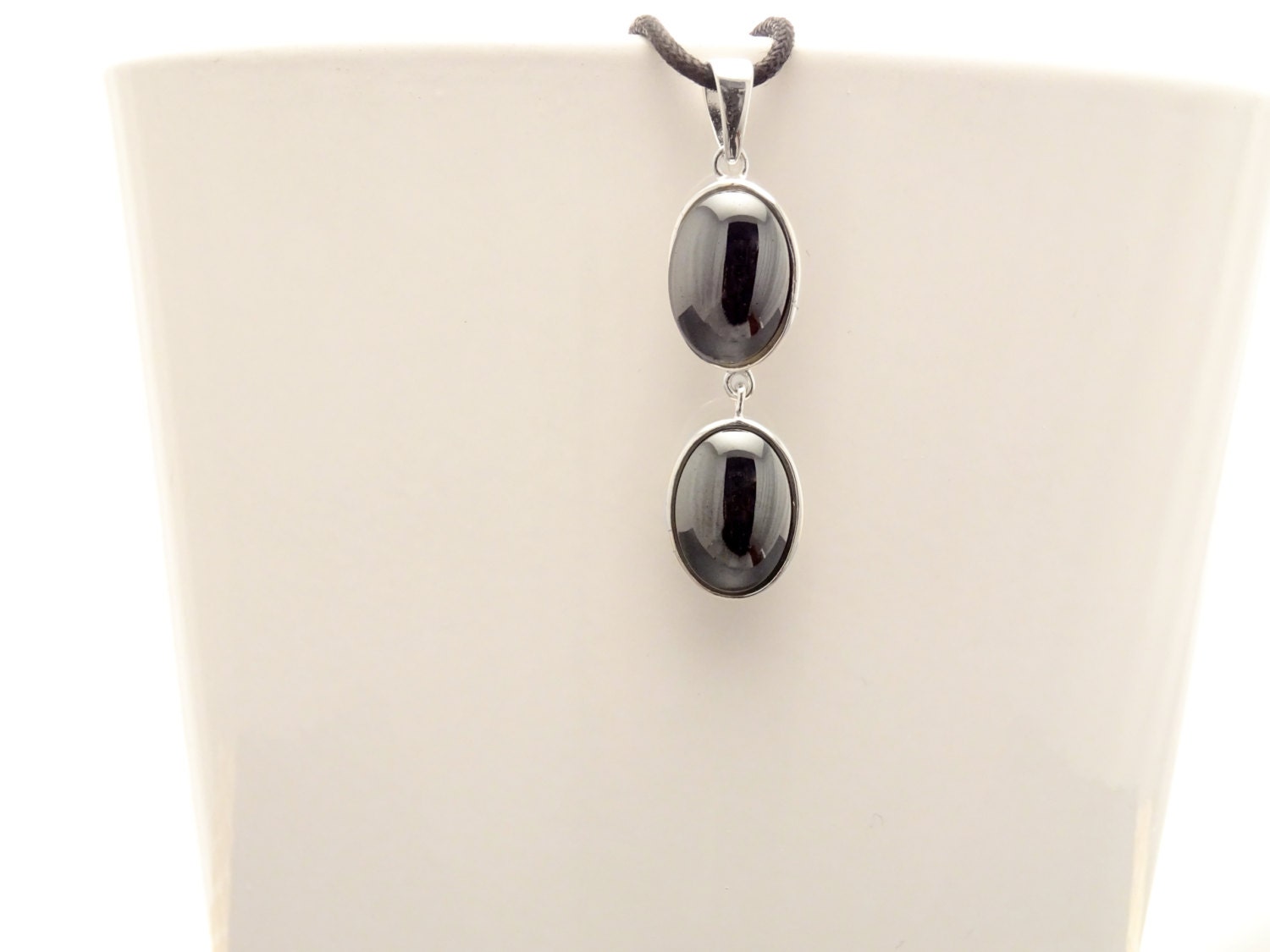 Peut inclure: Un collier avec un pendentif en argent avec deux pierres ovales noires.