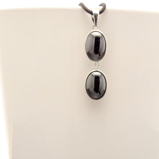 Peut inclure: Un collier avec un pendentif en argent avec deux pierres ovales noires.