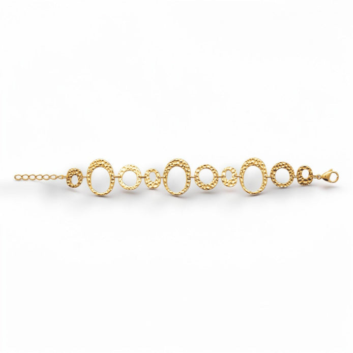 overview of a geometric bracelet opened
Product type: bracelet
Material:  18K Gold Filled, stainless steel base
Color: yellow gold
Style: statement, geometric, elegant, modern
Design details: hammered open circle and oval links, graduated sizes, textured finish, airy openwork design, lobster clasp with extender
Best for: statement styling, special occasions, everyday elevated wear, gifting, artistic jewelry lovers