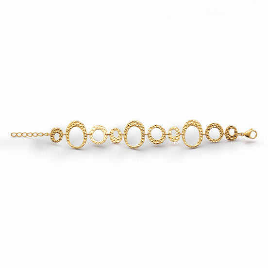 overview of a geometric bracelet opened
Product type: bracelet
Material:  18K Gold Filled, stainless steel base
Color: yellow gold
Style: statement, geometric, elegant, modern
Design details: hammered open circle and oval links, graduated sizes, textured finish, airy openwork design, lobster clasp with extender
Best for: statement styling, special occasions, everyday elevated wear, gifting, artistic jewelry lovers