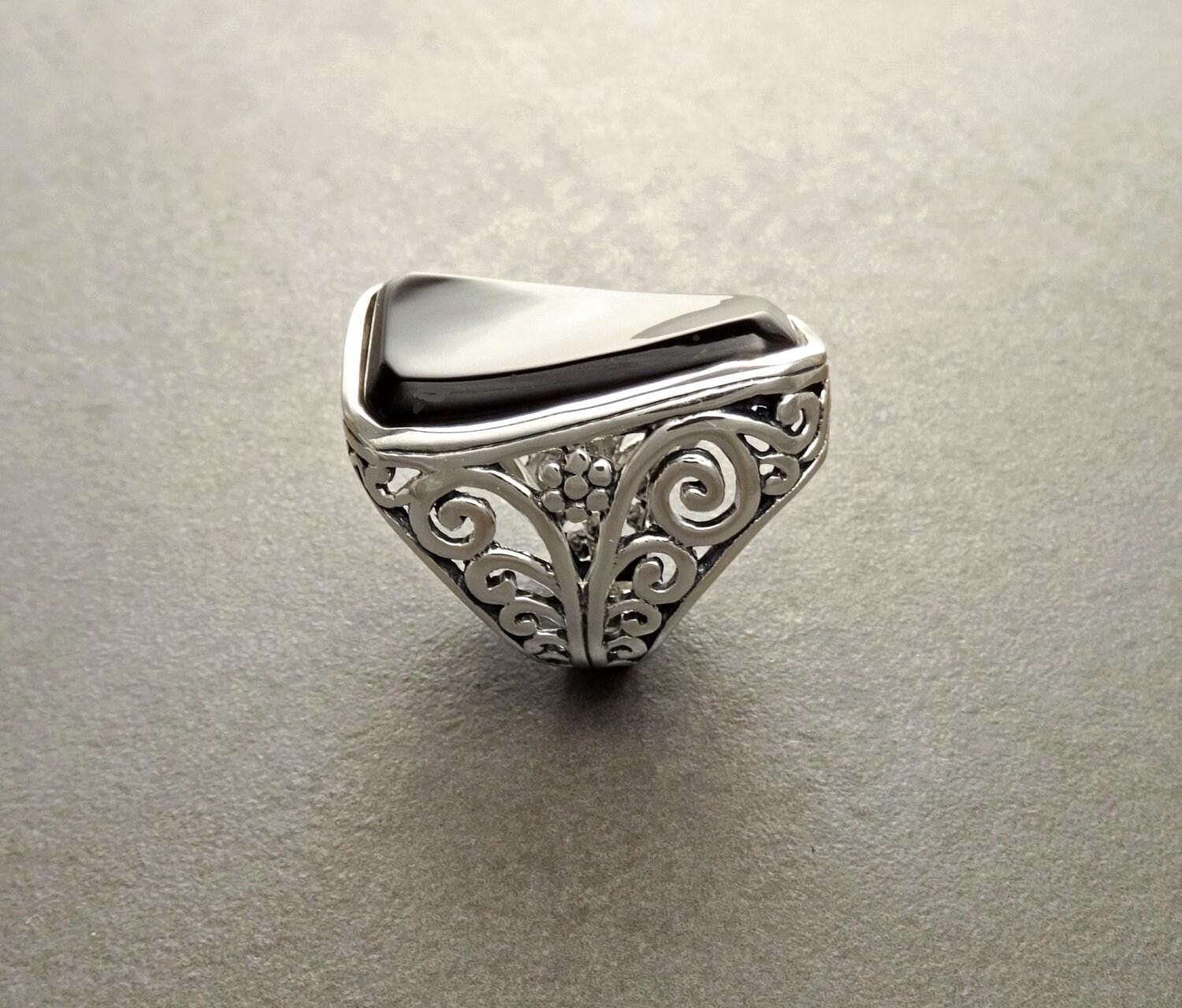 Une bague en argent 925 avec une pierre rectangulaire noir sertie dans un motif de filigrane vintage.