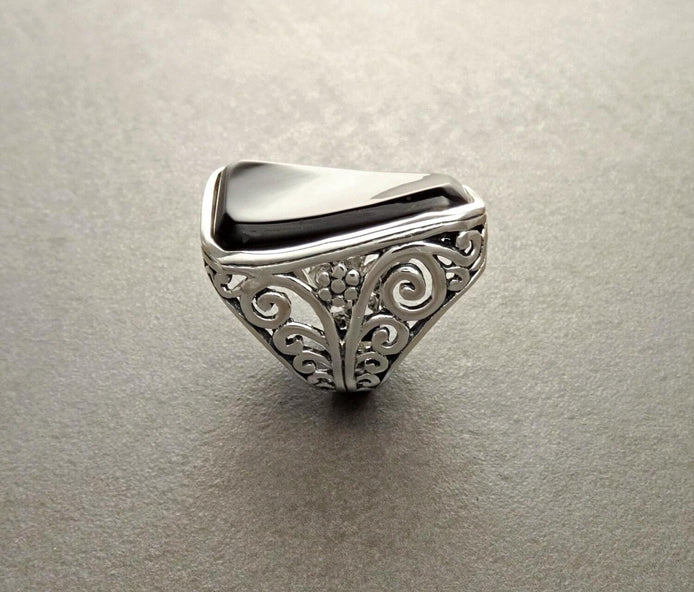 Une bague en argent 925 avec une pierre rectangulaire noir sertie dans un motif de filigrane vintage.