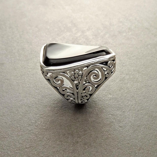 Une bague en argent 925 avec une pierre rectangulaire noir sertie dans un motif de filigrane vintage.