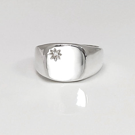 Peut inclure: Une bague signet en argent avec un petit diamant clair serti au centre en forme d'étoile.