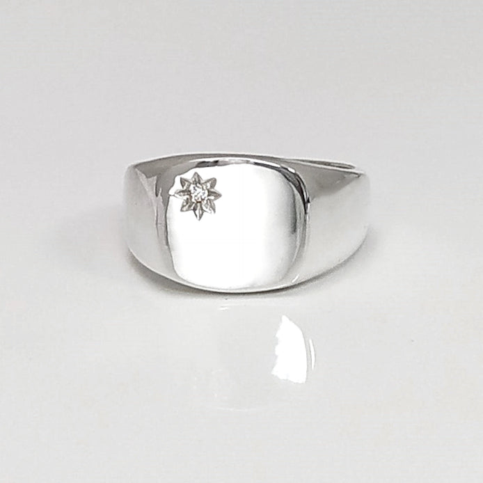 Peut inclure: Une bague signet en argent avec un petit diamant clair serti au centre en forme d'étoile.