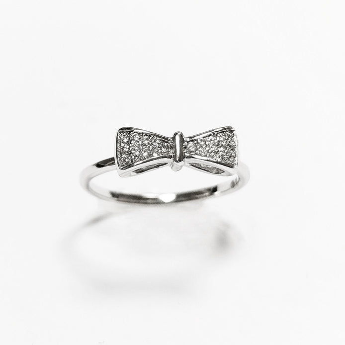 Peut inclure: Une bague en argent avec un motif en forme de nœud orné de petites pierres claires.