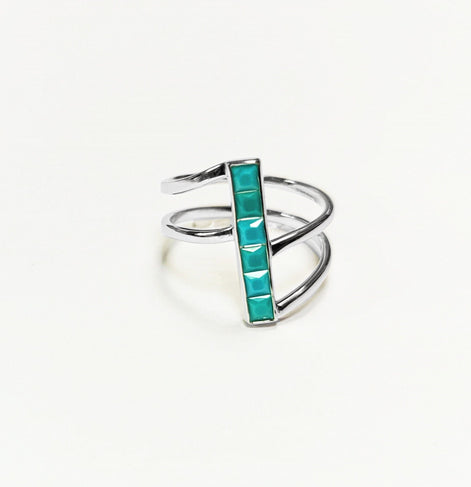 Peut inclure: Une bague en argent avec une pierre turquoise sertie dans un design de barre verticale. La bague a un design à triple bande.