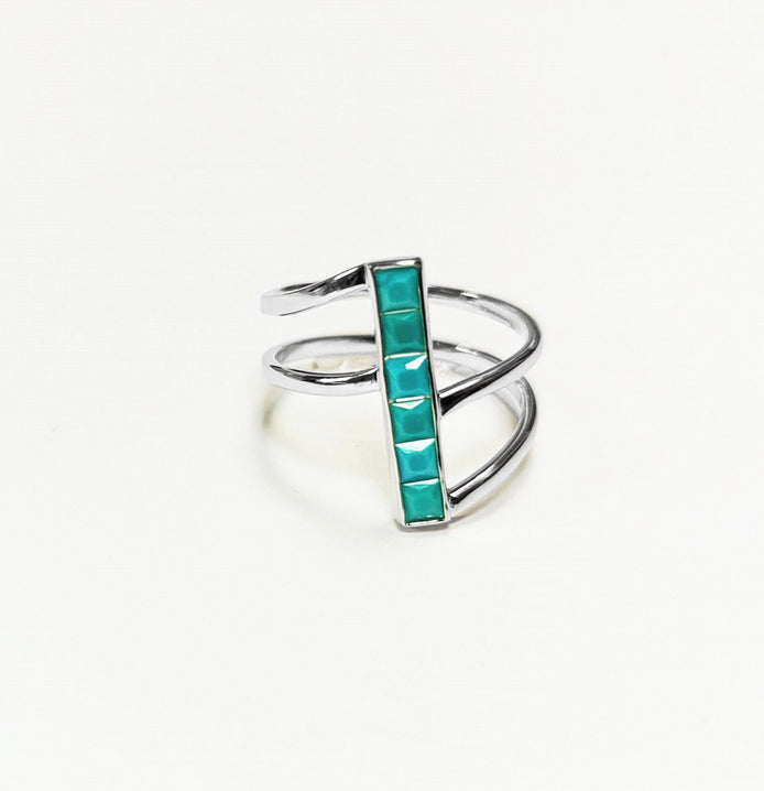 Peut inclure: Une bague en argent avec une pierre turquoise sertie dans un design de barre verticale. La bague a un design à triple bande.