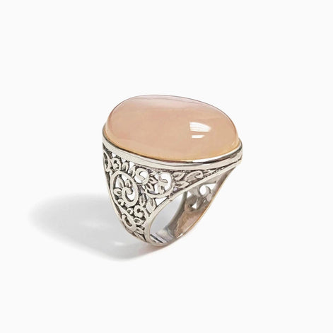 Peut inclure: Bague en argent ornée d'une pierre précieuse ovale rose pâle. La bague présente un motif filigrané élaboré sur le corps. La pierre est sertie dans un simple sertissage.