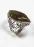 Peut inclure: Une bague en argent ornée d'une pierre ovale vert olive. La bague présente un motif floral ajouré sur le corps. La pierre est sertie dans un chaton en argent. La bague est présentée sur un fond blanc.