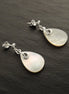 Une paire de boucles d'oreilles en argent avec des pendentifs en nacre blanche en forme de larme. Boucles d'oreilles de qualité, fabriquées à la main, par des petits créateurs de bijoux locaux reconnus (des milliers de ventes), avec des matériaux de qualité et durable. Un achat en toute confiance dans une boutique avec des milliers d'avis positifs.