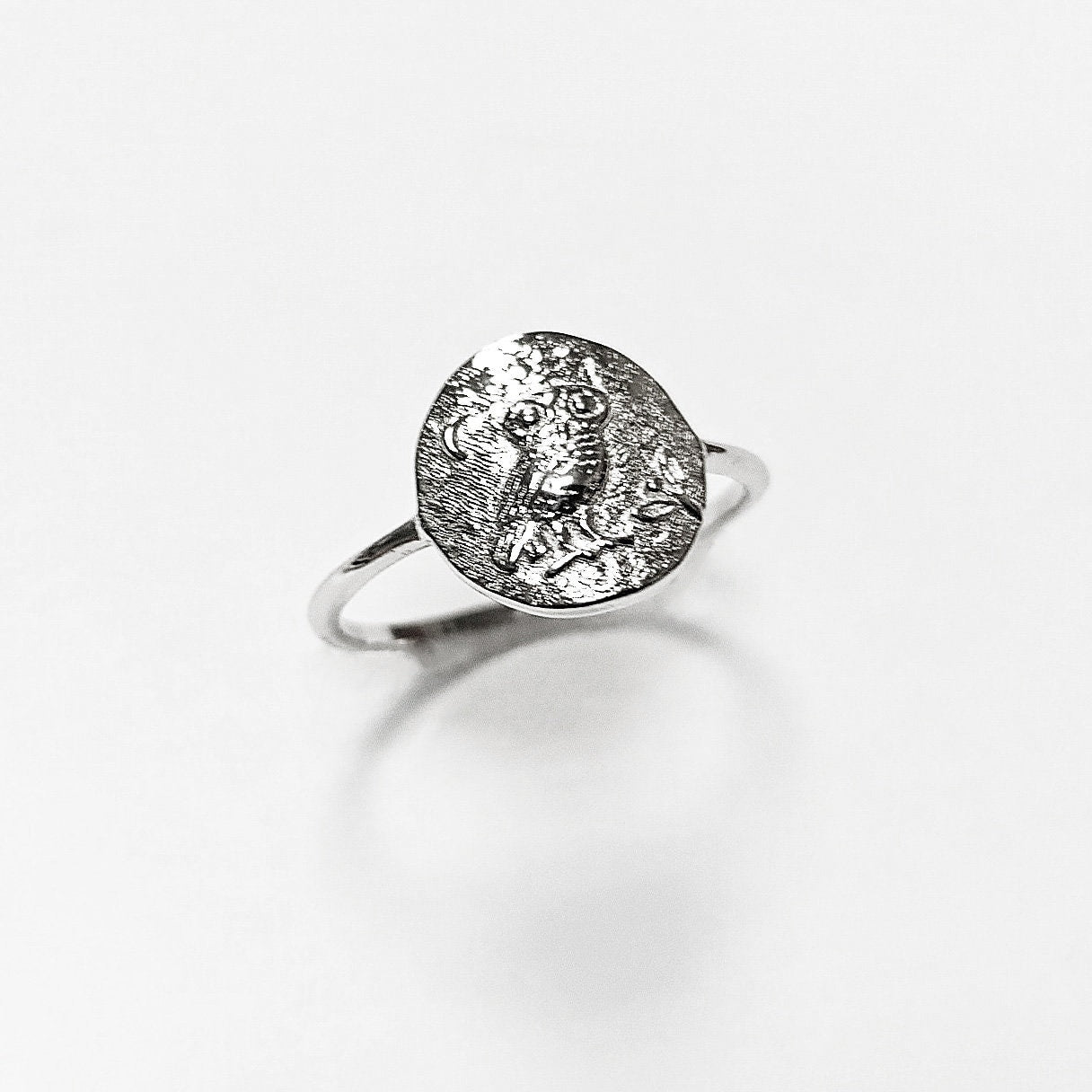 Peut inclure: Une bague en argent avec un motif ovale représentant un hibou perché sur une branche. Le hibou a des détails précis et est entouré d'un croissant de lune.