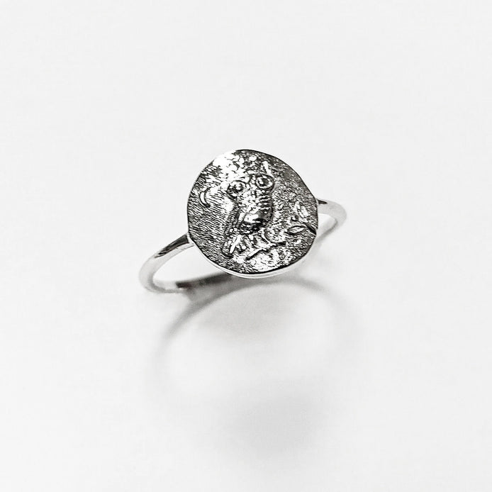 Peut inclure: Une bague en argent avec un motif ovale représentant un hibou perché sur une branche. Le hibou a des détails précis et est entouré d'un croissant de lune.